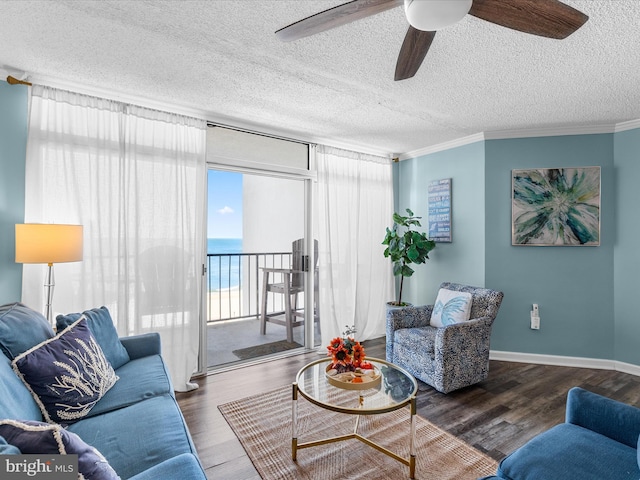 living room featuring dark wood-style flooring, a water view, ornamental molding, a textured ceiling, and baseboards