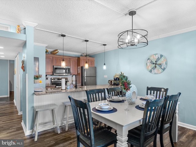 dining room featuring dark wood-type flooring, crown molding, a textured ceiling, and baseboards