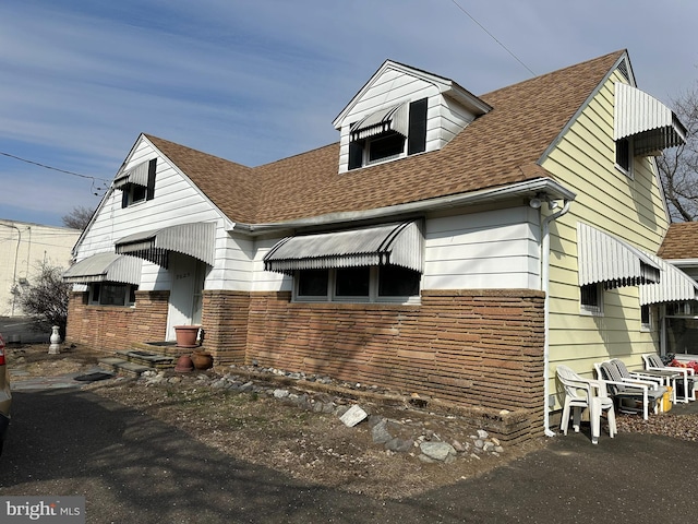 view of front of house with a shingled roof and stone siding