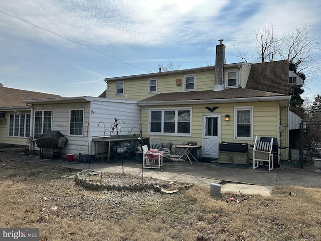 rear view of property featuring a shingled roof, a chimney, and a patio area