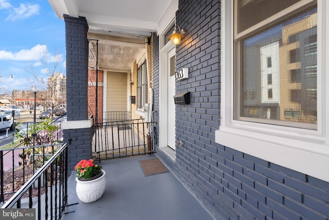 entrance to property with covered porch and brick siding