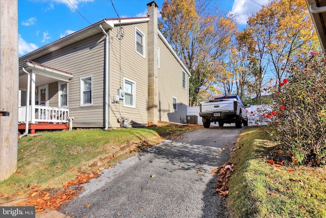 view of home's exterior featuring central air condition unit, covered porch, and a lawn