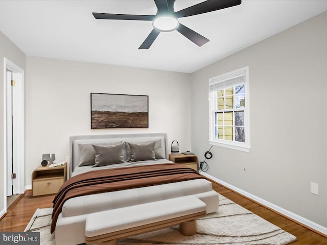 bedroom with a ceiling fan, baseboards, and wood finished floors