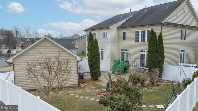 back of property with a fenced backyard and a lawn