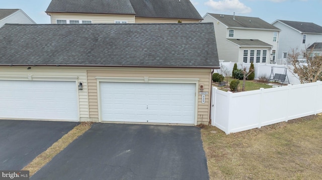 garage with fence and aphalt driveway