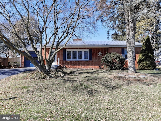 ranch-style house with driveway, brick siding, a chimney, an attached garage, and a front yard