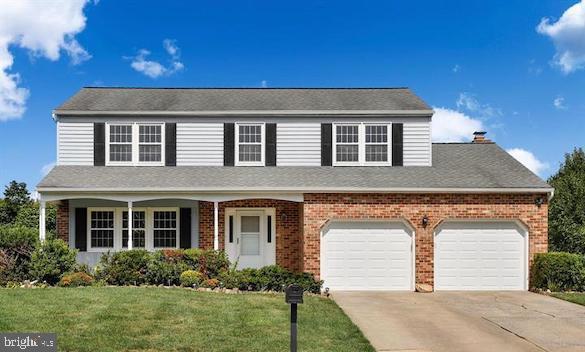 traditional-style house with driveway, a garage, a front yard, and brick siding