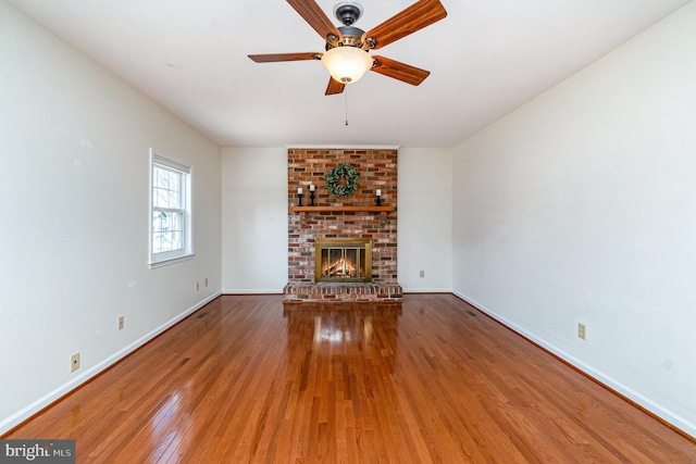 unfurnished living room featuring ceiling fan, hardwood / wood-style floors, a fireplace, and baseboards