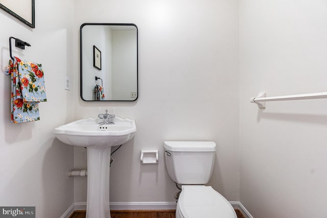 half bath featuring toilet and baseboards