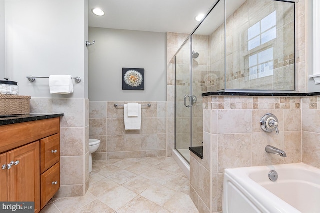 full bathroom featuring a wainscoted wall, a garden tub, tile walls, a shower stall, and vanity