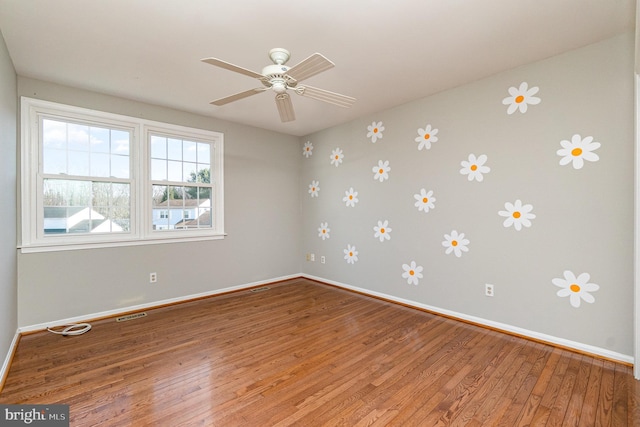 spare room with hardwood / wood-style flooring, ceiling fan, visible vents, and baseboards