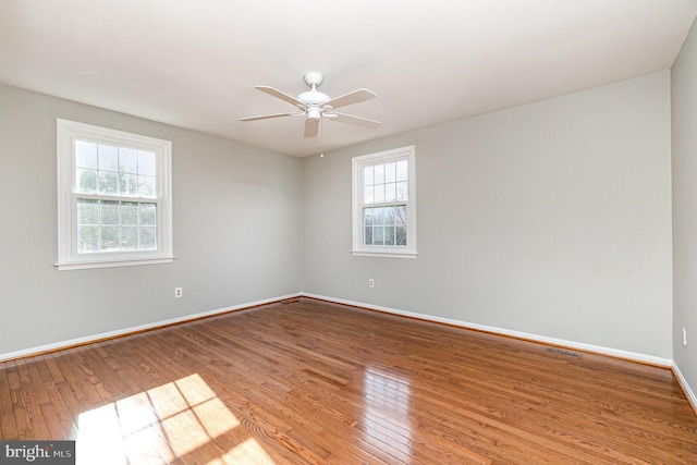 spare room featuring a healthy amount of sunlight, wood-type flooring, and baseboards