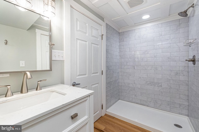 bathroom featuring visible vents, tiled shower, and vanity