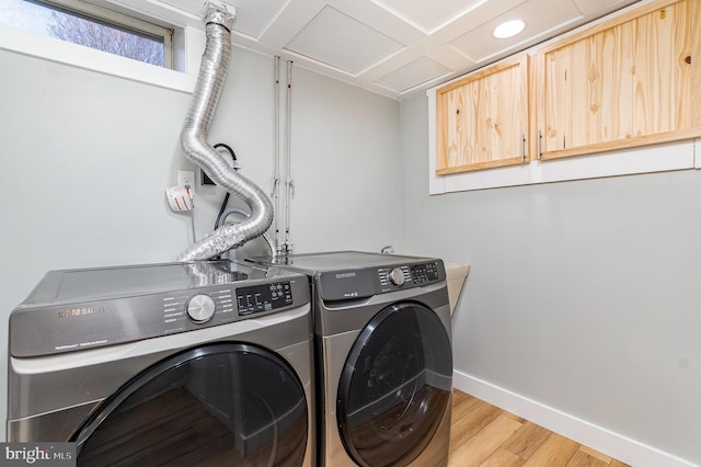 laundry room with light wood finished floors, washing machine and dryer, cabinet space, and baseboards