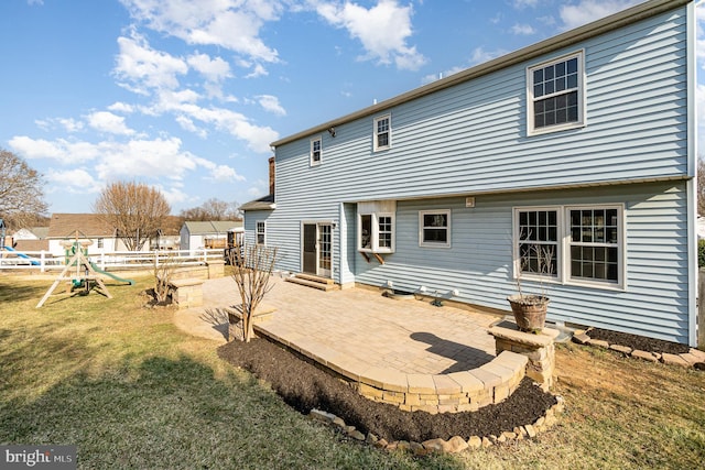 back of property with entry steps, a patio, fence, a yard, and a playground