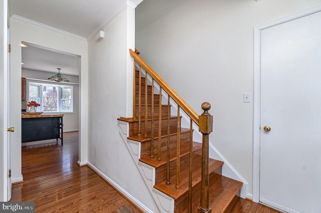 staircase with baseboards, ornamental molding, and wood finished floors