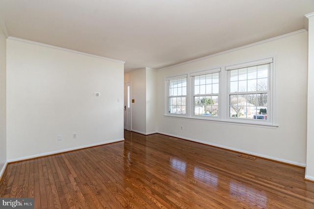 empty room featuring visible vents, crown molding, baseboards, and hardwood / wood-style flooring