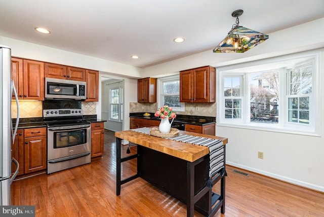 kitchen with dark countertops, visible vents, appliances with stainless steel finishes, wood finished floors, and baseboards