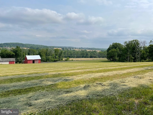 view of yard featuring an outbuilding, a rural view, and a view of trees