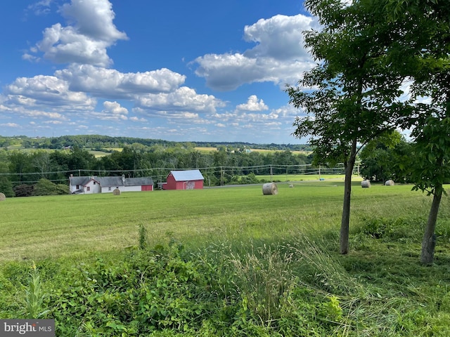 view of yard featuring an outbuilding, a rural view, and fence