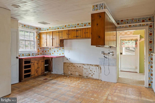 kitchen with a sink, visible vents, wood ceiling, brown cabinets, and decorative backsplash