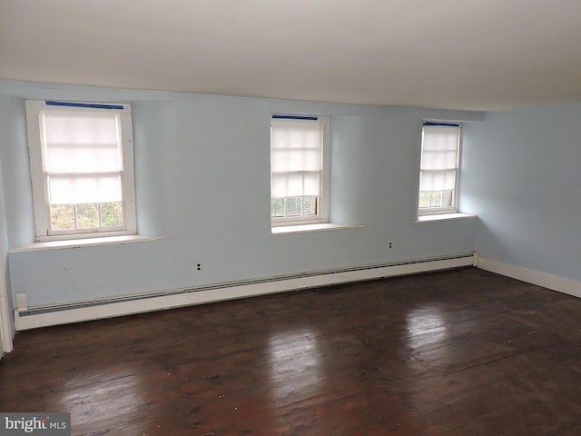 empty room featuring a baseboard radiator, baseboards, a healthy amount of sunlight, and hardwood / wood-style floors