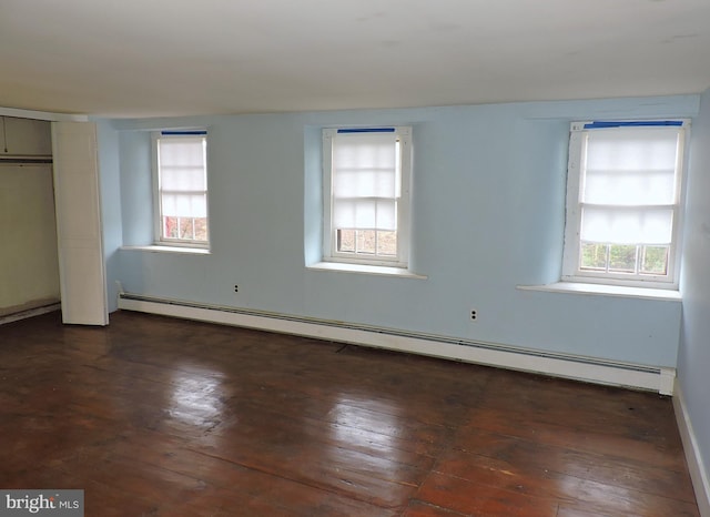 unfurnished bedroom featuring wood-type flooring, multiple windows, baseboard heating, and a closet