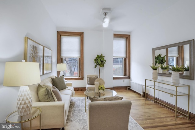 living area with a wealth of natural light, radiator, baseboards, and wood finished floors