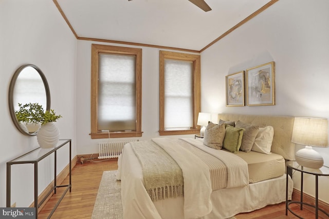 bedroom featuring ornamental molding, radiator, multiple windows, and light wood-style flooring