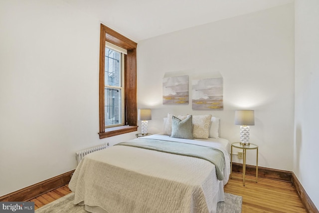 bedroom featuring radiator, baseboards, and wood finished floors