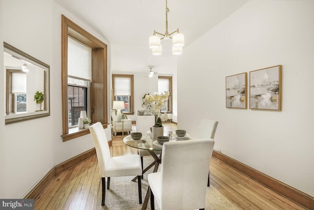 dining area featuring an inviting chandelier, light wood-style flooring, and baseboards