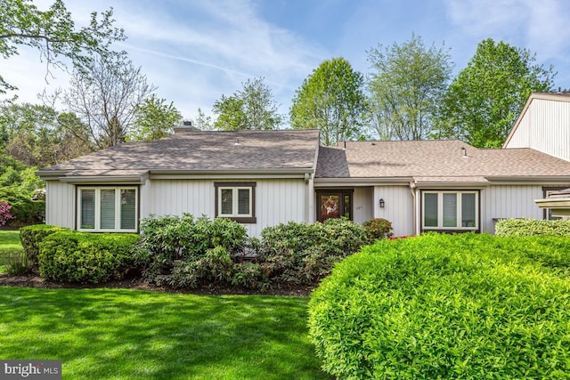 view of front of property featuring roof with shingles, a chimney, and a front lawn
