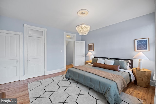 bedroom featuring light wood-style floors, baseboards, and a chandelier