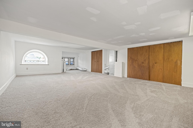 unfurnished living room featuring carpet floors and baseboards