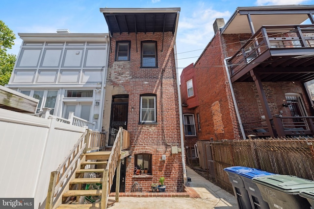 townhome / multi-family property featuring a fenced backyard, stairs, and brick siding