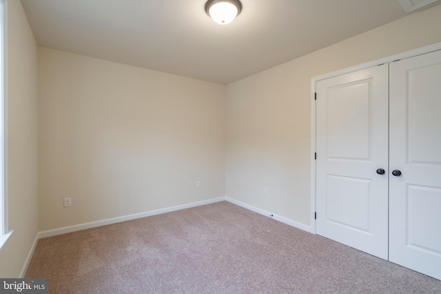 unfurnished bedroom with light carpet and a closet