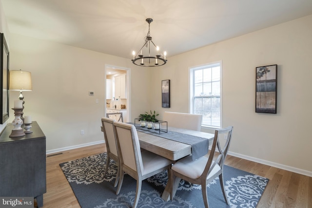 dining area with light hardwood / wood-style floors and an inviting chandelier