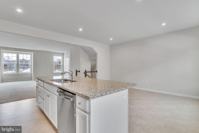 kitchen featuring a center island with sink, white cabinets, open floor plan, stainless steel dishwasher, and a sink