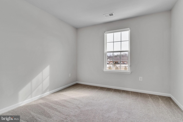 carpeted spare room featuring visible vents and baseboards