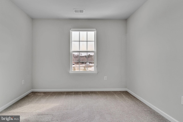 spare room with carpet floors, visible vents, and baseboards