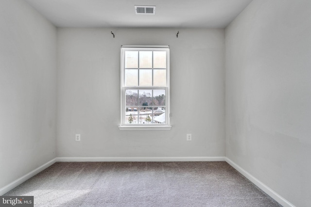 spare room featuring carpet floors, visible vents, and baseboards