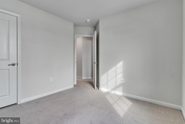 unfurnished bedroom featuring light carpet and baseboards