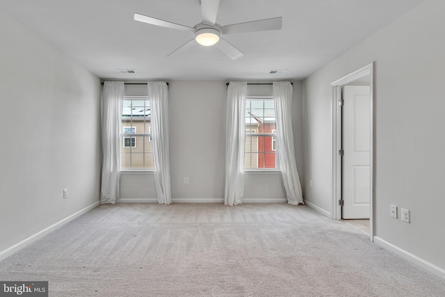 empty room featuring light carpet, ceiling fan, visible vents, and baseboards