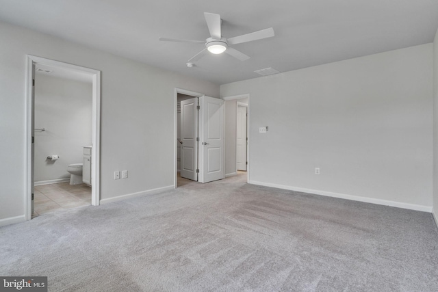 unfurnished bedroom with baseboards, ensuite bath, and light colored carpet