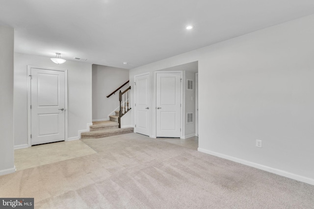 interior space with light carpet, visible vents, stairway, and baseboards