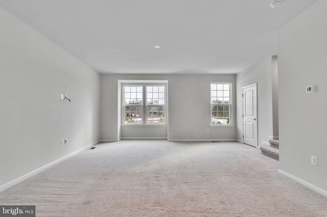 unfurnished living room with light carpet, stairs, and baseboards