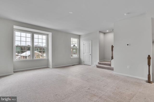 unfurnished living room featuring light colored carpet, baseboards, and stairs