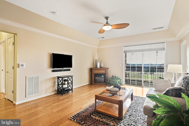 living area with baseboards, visible vents, and wood finished floors