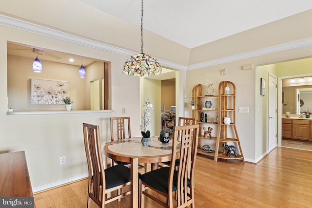 dining room featuring crown molding, light wood finished floors, and baseboards