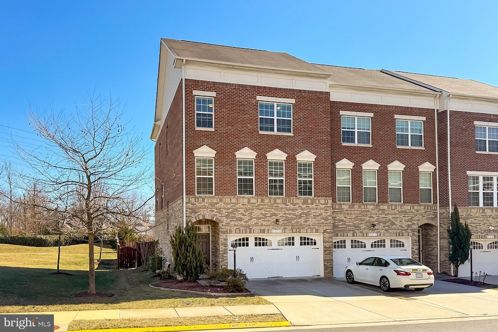 23210 Tradewind Dr, Brambleton, VA 20148 - townhome / multi-family property with driveway, stone siding, a front yard, an attached garage, and brick siding